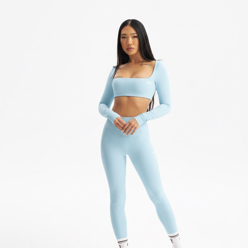 Woman wearing a light blue athletic outfit on a white background