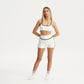 Woman wearing a white sports bra and shorts set on a white background