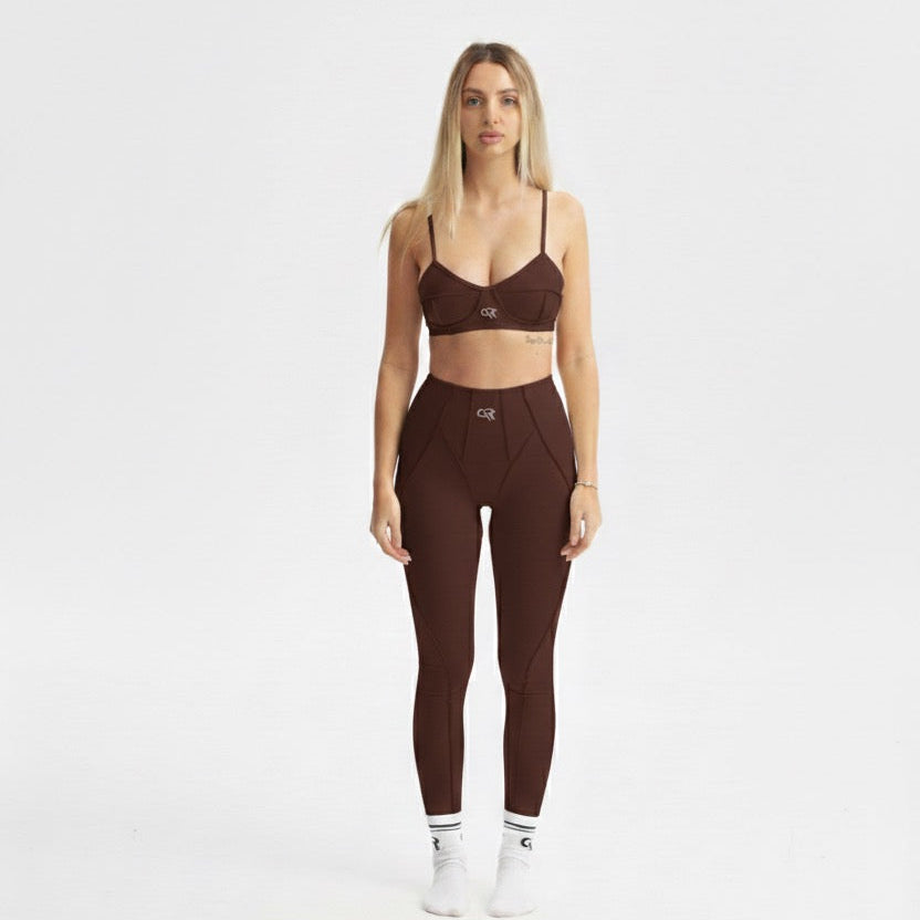 Woman wearing a brown sports bra and leggings set on a white background