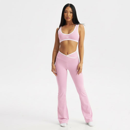 Person wearing a pink sports bra and pants on a white background