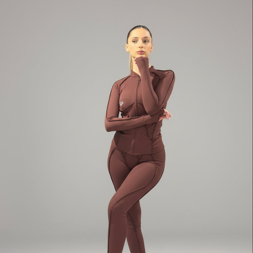 Woman wearing a brown athletic outfit on a gray background